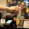 Hand placing a dollar in a tip jar