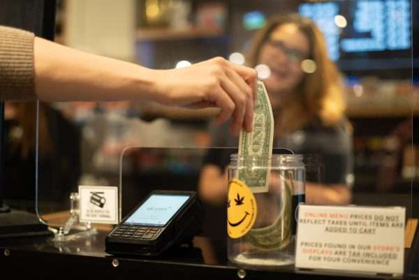 Hand placing a dollar in a tip jar