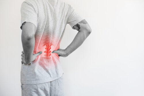 A person holding onto their lower back, which is superimposed with a red spine and coloring to indicate back pain.