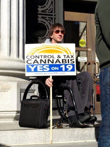 Richard Lee holding a "Yes on 19" poster in front of the Alameda County Courthouse in 2009